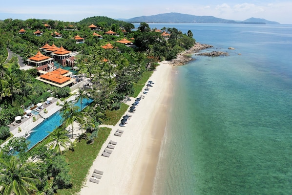 Vista aérea de un resort con playa, piscina y villas.