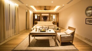 A hotel room with a large bed, a sitting area with a coffee table, and a view of the cityscape through the window.