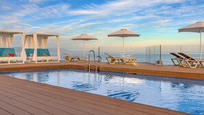 A poolside area with lounge chairs, umbrellas, and a glass-enclosed cabana. - AluaSun Lago Rojo - Adults Recommended (Torremolinos)