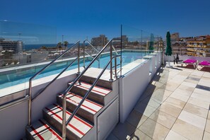 A rooftop pool with glass railings, red and white striped steps, and a view of the city and sea. - Hotel Ritual Sireno Torremolinos - Adults Only (Torremolinos)