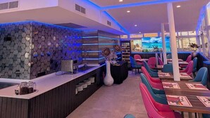 Un restaurante con un diseño moderno de techo, una zona de bar y asientos coloridos.