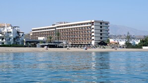 Un hotel con varios pisos, balcones y ubicación frente a la playa.