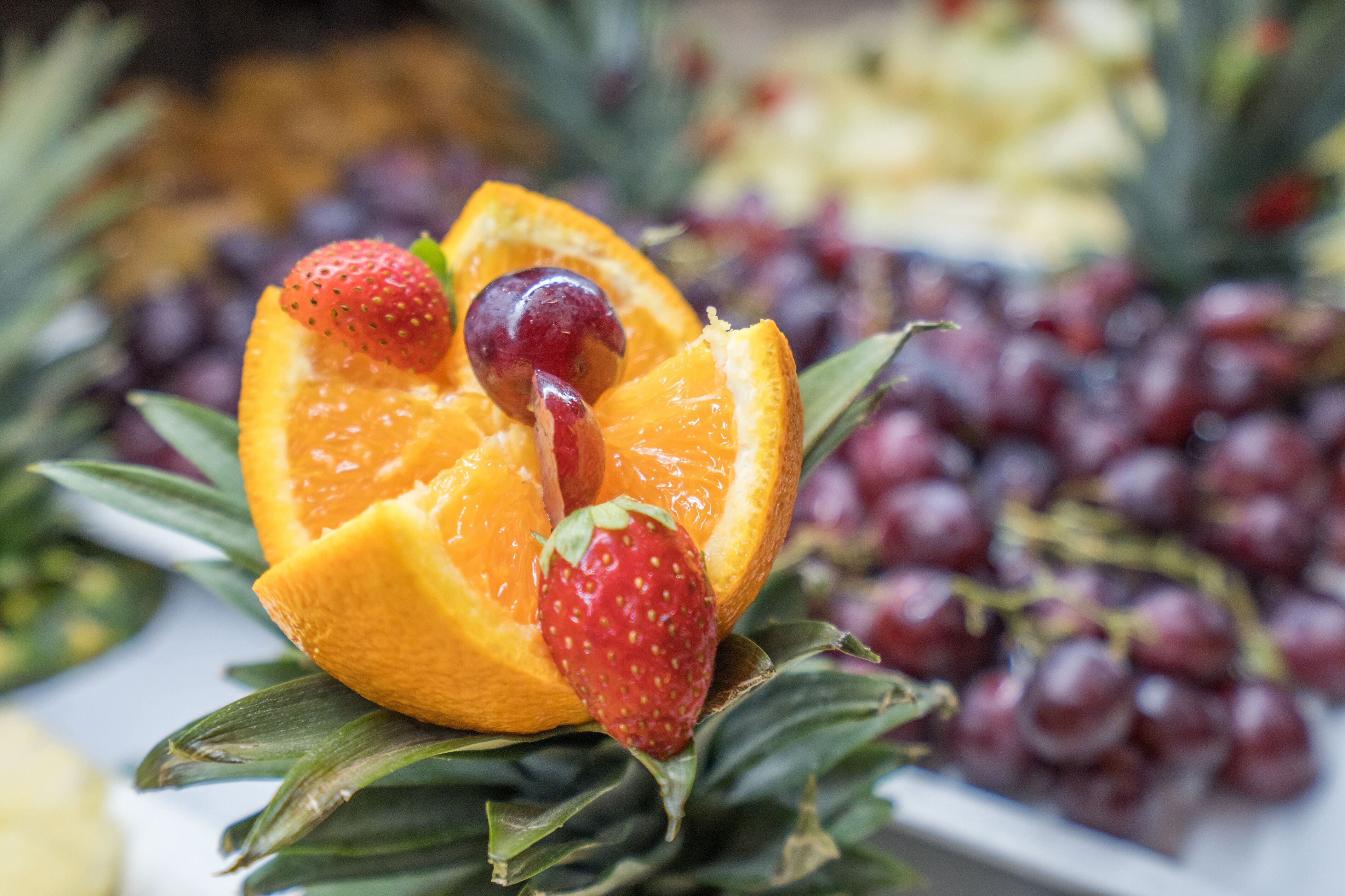 A fruit arrangement with strawberries, grapes, and orange slices on a plate.