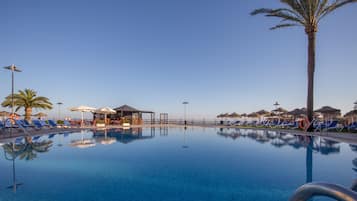 Una piscina al aire libre, sombrillas, sillones reclinables de piscina