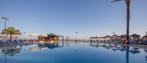 Una piscina al aire libre, sombrillas, tumbonas