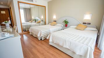 A hotel room with two beds, a desk with a computer, and a large mirror.