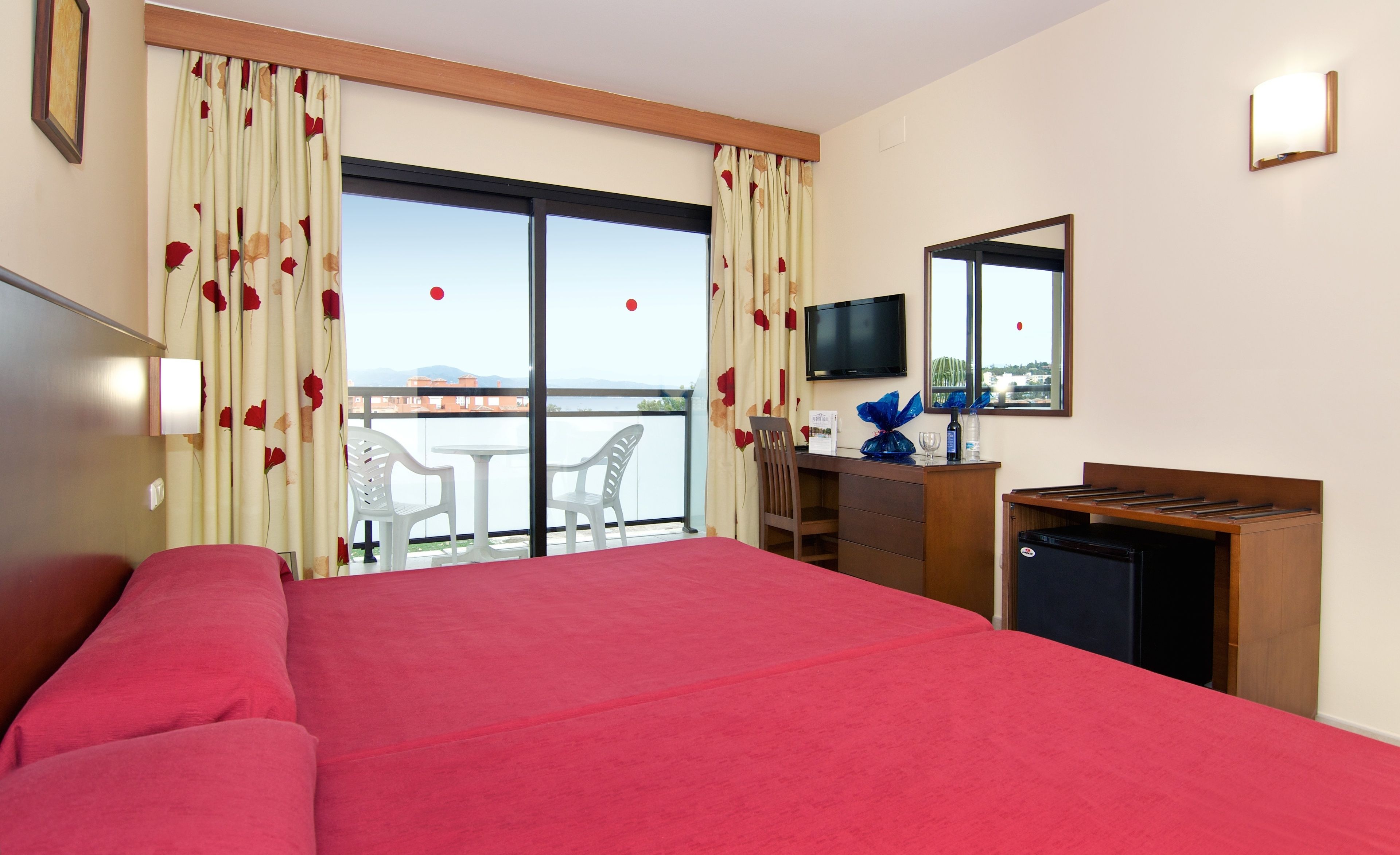 Ein Hotelzimmer mit Bett, Schreibtisch, Stuhl, Fernseher und einem Balkon mit Blick.