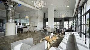 A spacious lobby with modern furniture, large windows, and decorative lighting. - Hotel Puente Real (Torremolinos)