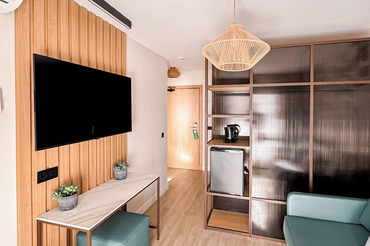 Una sala de estar moderna con una televisión de pantalla plana, paneles de madera, una zona de comedor, una kitchenette y un ventanal grande.