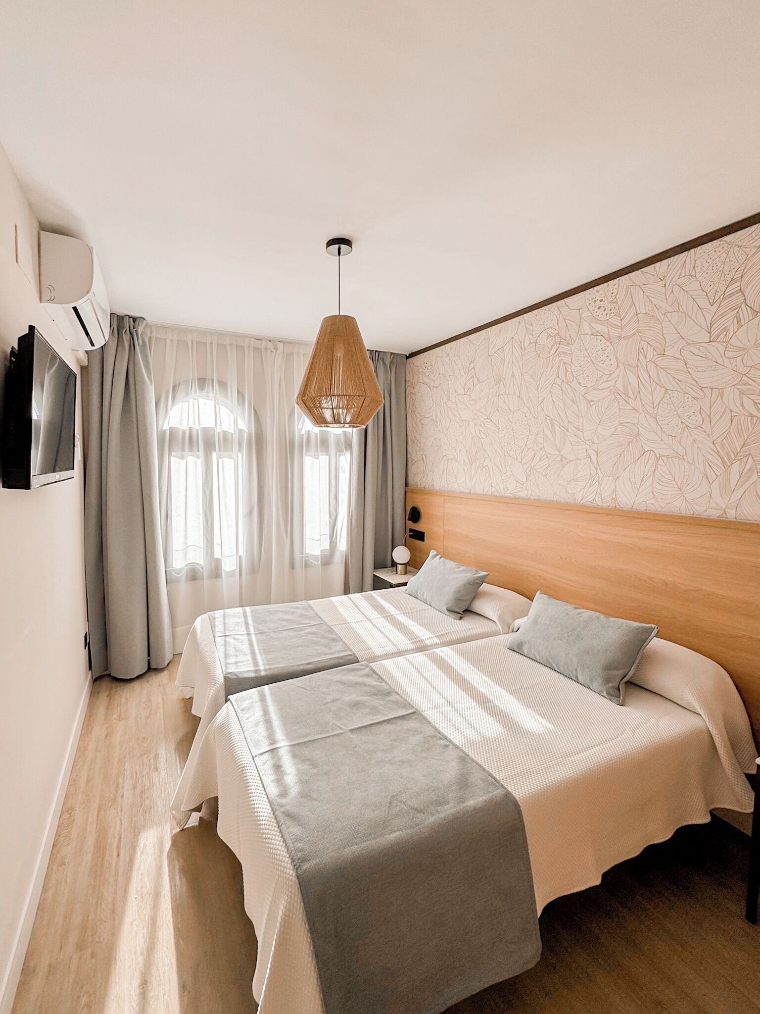 A hotel room with a large bed, a bedside table with a lamp, and a wall-mounted TV.