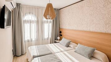 A hotel room with a large bed, a bedside table with a lamp, and a wall-mounted TV.