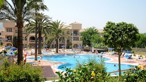 A pool area with multiple swimming pools, palm trees, and lounge chairs. - Hotel Puente Real (Torremolinos)