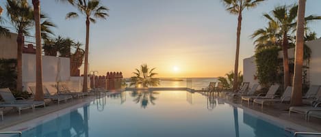 Una piscina techada, una piscina al aire libre, sombrillas