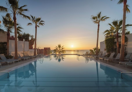 Una piscina techada, una piscina al aire libre, sombrillas