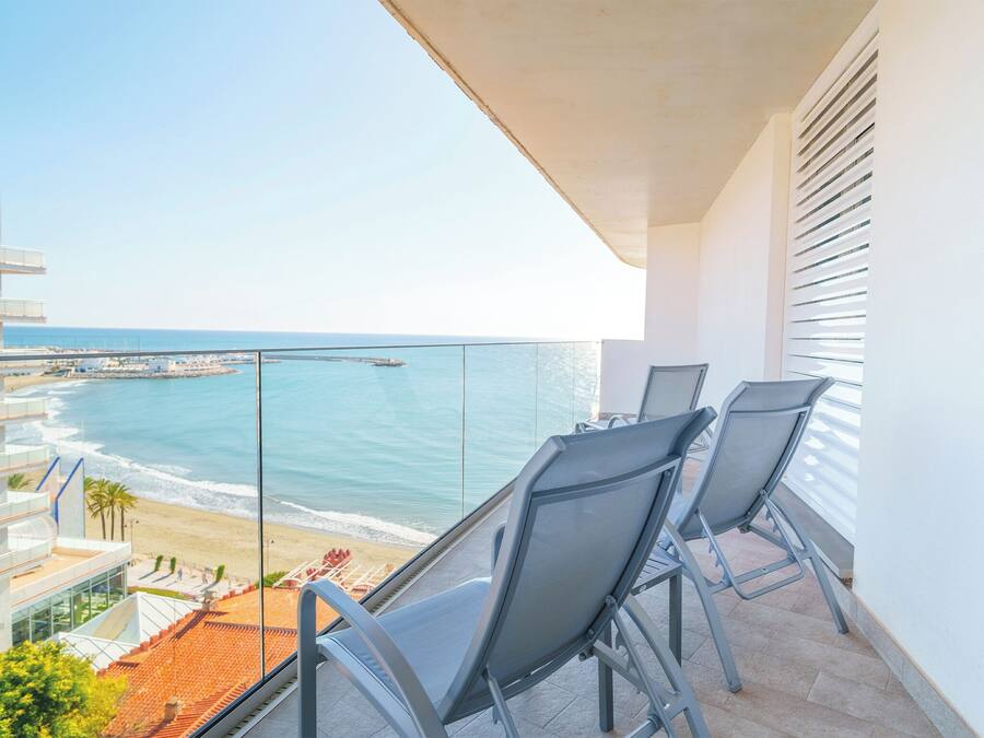 En balkon med to stole med udsigt over en strand og havet.