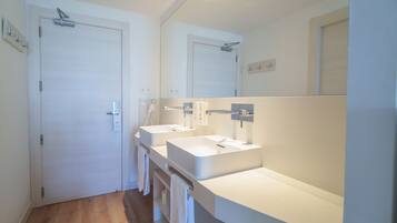 Une salle de bain moderne avec deux lavabos, un grand miroir et une douche.