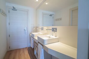 Une salle de bain moderne avec deux lavabos, un grand miroir et une douche.