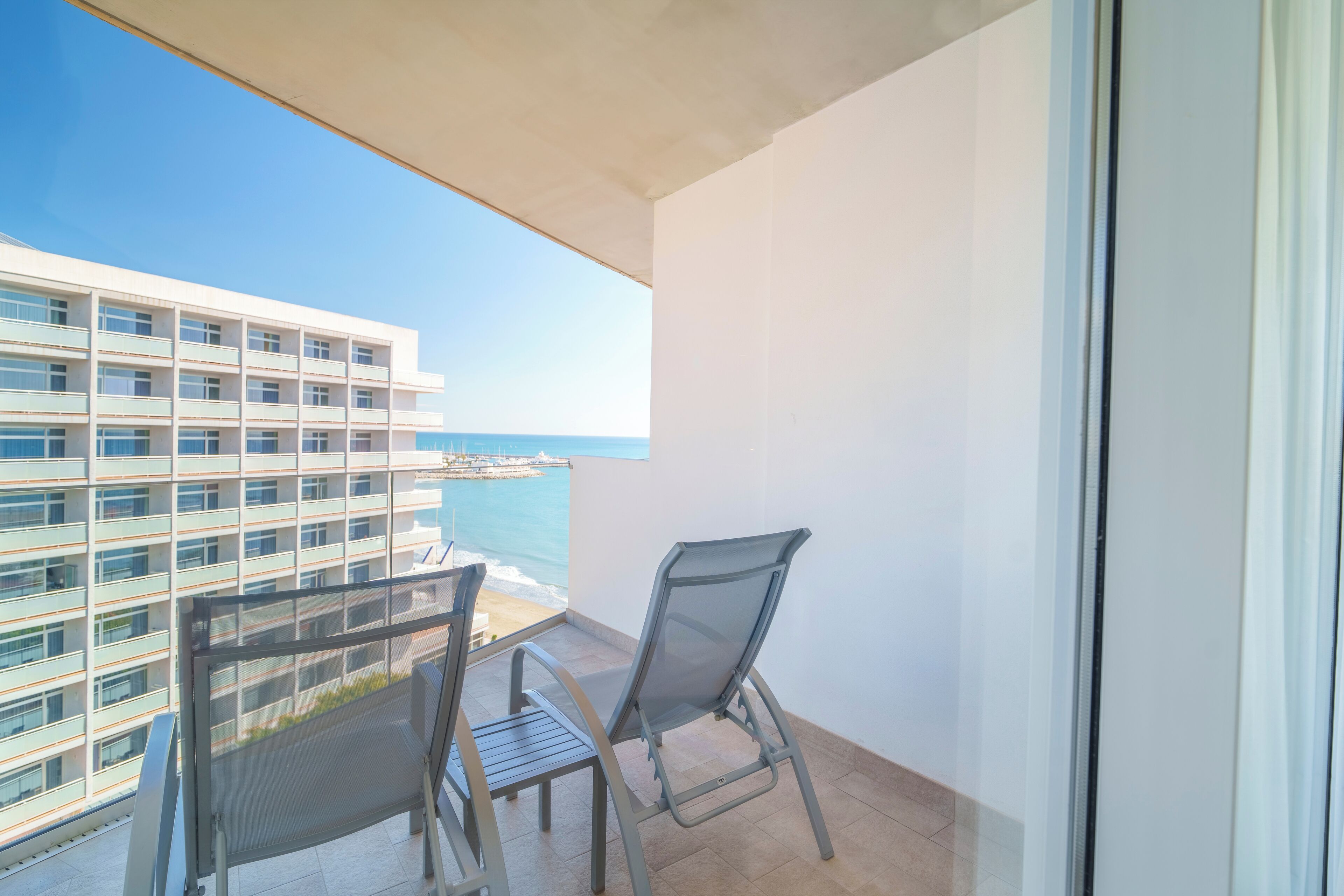 A balcony with a view of the sea and a high-rise building.