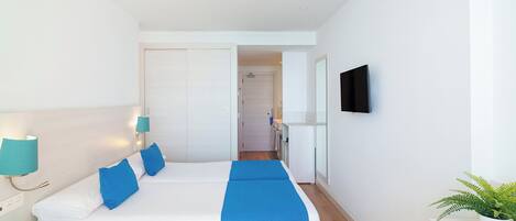 A hotel room with a large bed, a TV mounted on the wall, and a potted plant.