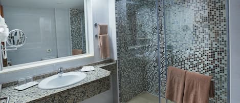A modern bathroom with a glass-enclosed shower, a large mirror, and a granite countertop.