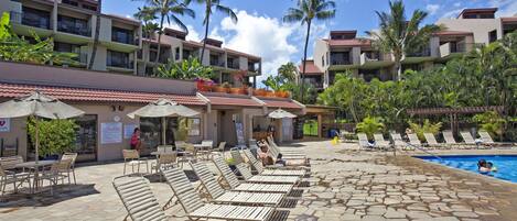 A poolside area with lounge chairs, umbrellas, and a swimming pool.