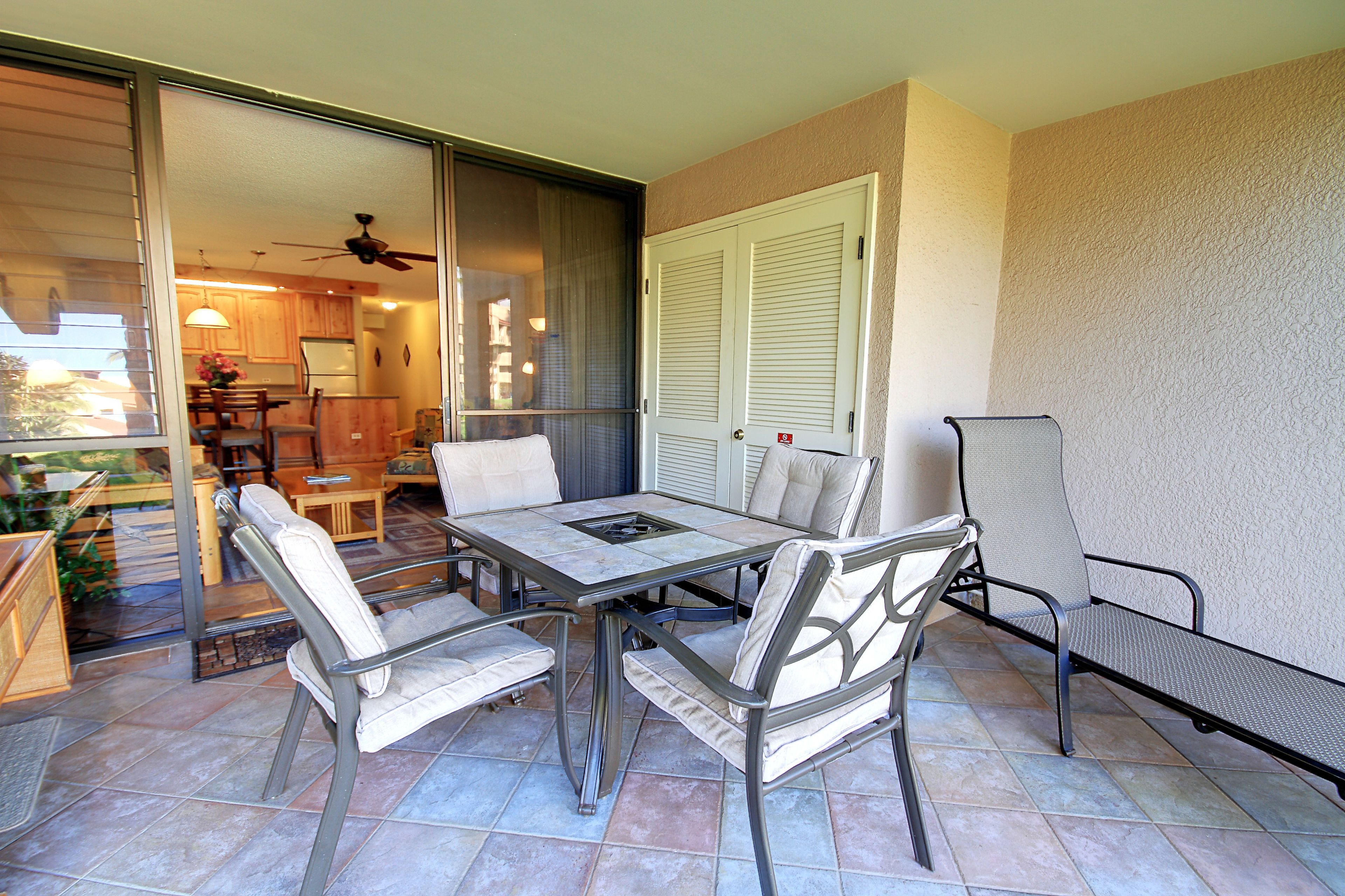 A patio with a table and chairs, a sliding glass door leading to a kitchen, and a ceiling fan.