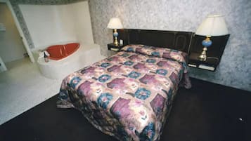Een slaapkamer met een bed, twee bedlampen, een nachtkastje en een rode badkuip.