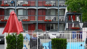 Un hotel de varios pisos con balcones, piscina y mobiliario exterior.