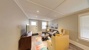 Una sala de estar moderna con un sofá, sillones, una mesa de centro y un televisor.