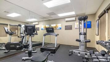 A gym with cardio machines, weight benches, and dumbbells.