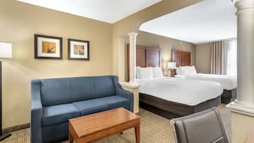 Un cuarto de hotel con una cama grande, un sofá azul, una mesa de centro de madera y dos cuadros en la pared.