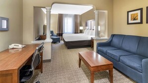 Een hotelkamer met een bed, een blauwe bank, een houten bureau, een stoel en een kleine tafel.