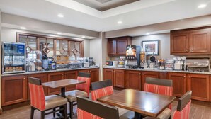 Een restaurantgedeelte in een hotel met een buffetopstelling, houten kasten en zitplaatsen.