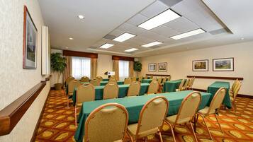 Una sala conferenze con tavoli e sedie, una moquette a motivi e luci a soffitto.