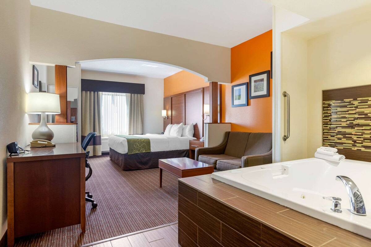 Une chambre d’hôtel équipée d’un lit, d’un bureau, d’une chaise et d’une grande salle de bain avec baignoire.