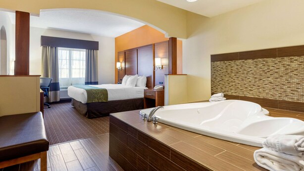 Een hotelkamer met een groot bad, een bed, een bureau en een stoel.