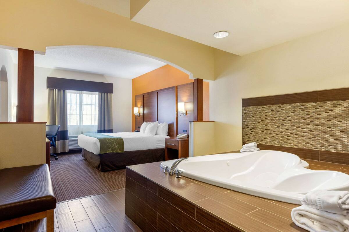 Une chambre d’hôtel avec une grande baignoire, un lit, un bureau et une chaise.