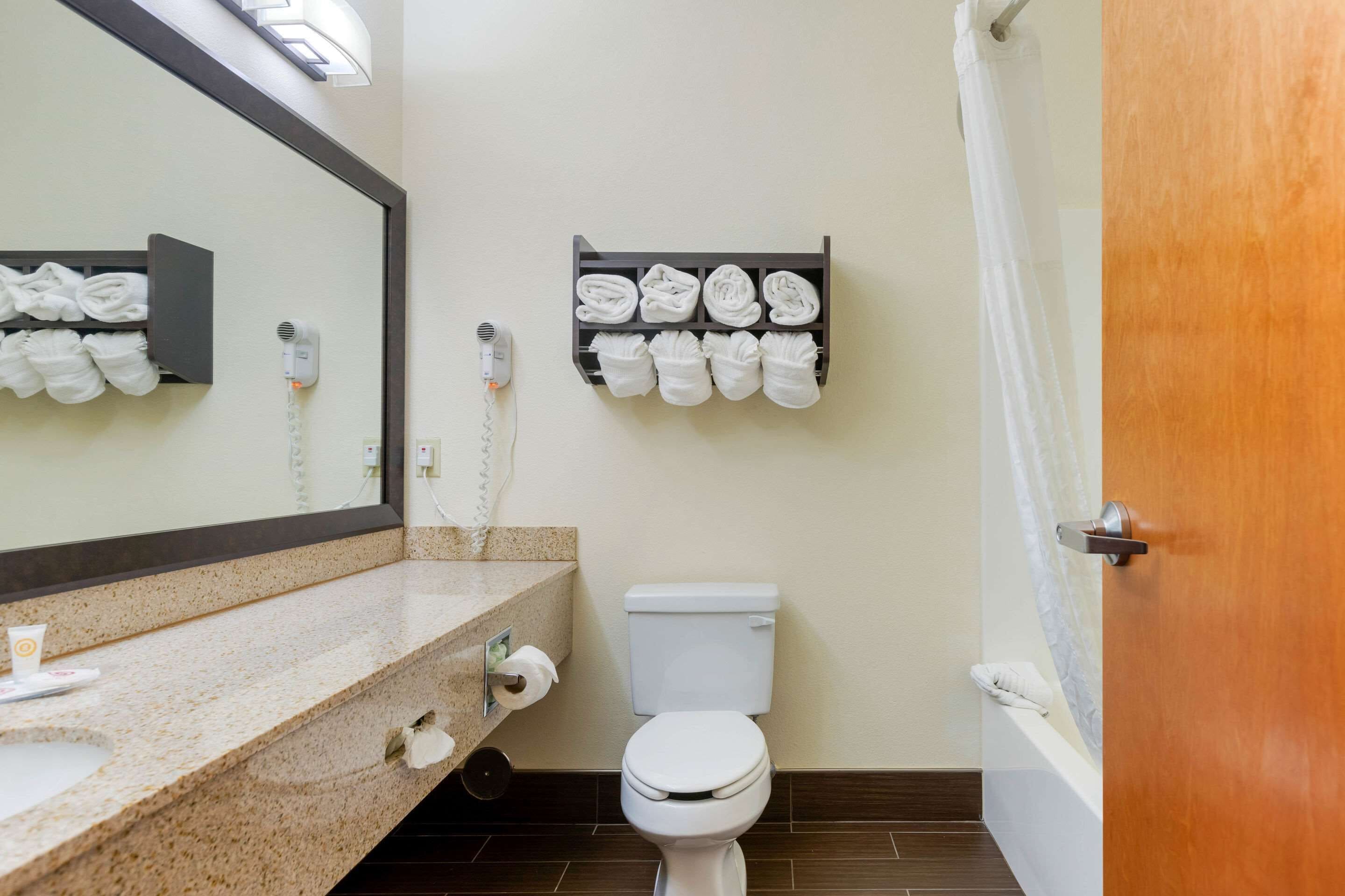 A bathroom with a sink, mirror, towel rack, toilet, and a shower curtain.