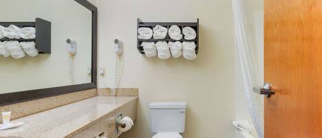A bathroom with a sink, mirror, towel rack, toilet, and a shower curtain.