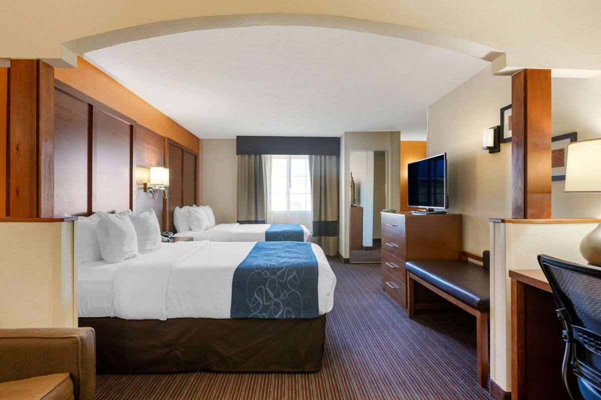 Une chambre d’hôtel avec deux lits, un bureau, une télévision et un grand miroir.