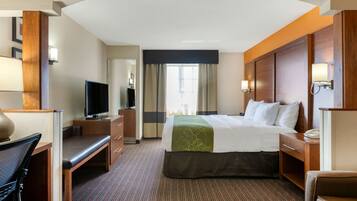 A hotel room with a bed, a desk, a television, and a window with curtains.