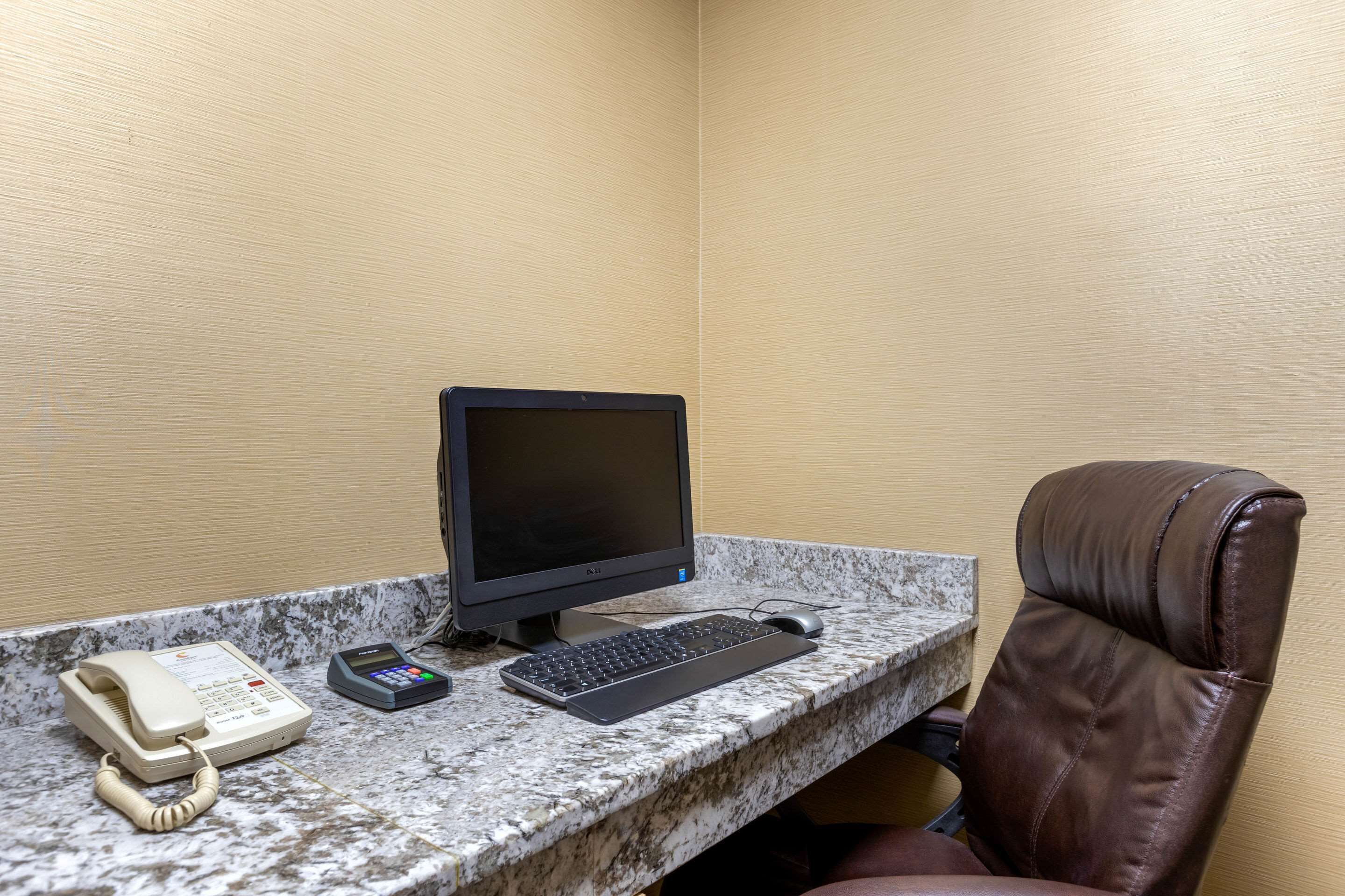 Oficina en esquina con computadora de escritorio, teléfono y una silla.