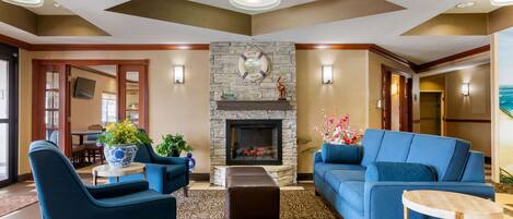 A lobby with a stone fireplace, blue sofas, and a patterned carpet.