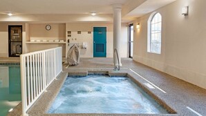 Een wellnessruimte met een bubbelbad, een klok en een blauwe deur.