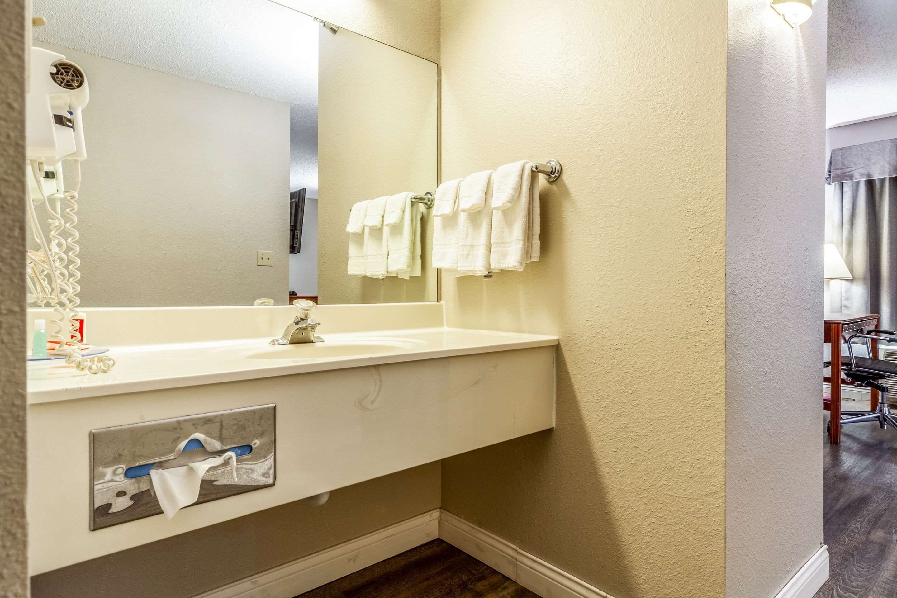 Un bagno con un lavandino bianco, uno specchio e due asciugamani su un portasciugamani.