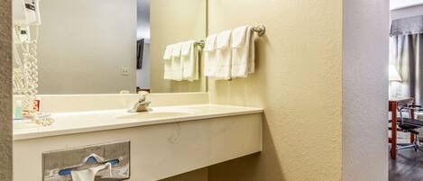 Un bagno con un lavandino bianco, uno specchio e due asciugamani su un portasciugamani.