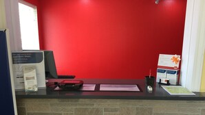 A reception desk with a red wall, a computer, a printer, and informational brochures. - Econo Lodge Lincoln (Lincoln)