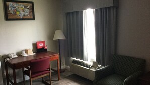 A hotel room with a desk, chair, lamp, and a window with curtains. - Econo Lodge Lincoln (Lincoln)