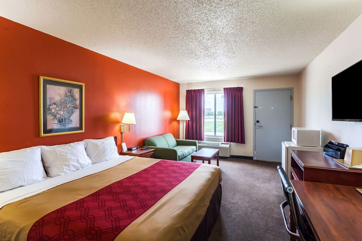 A hotel room with a bed, a desk, a chair, a television, and a window with curtains.