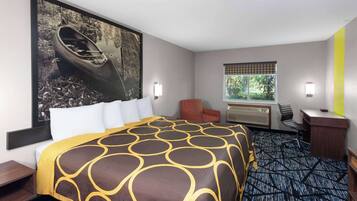 A hotel room with a large bed, a desk, a chair, and a window.